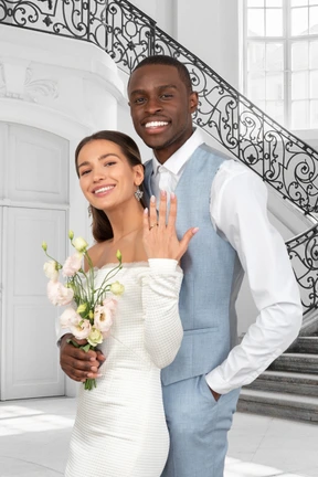 A bride and a groom standing in front of a staircase