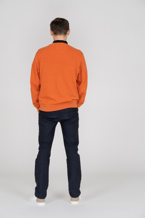 Junger mann im orangefarbenen sweatshirt stehend