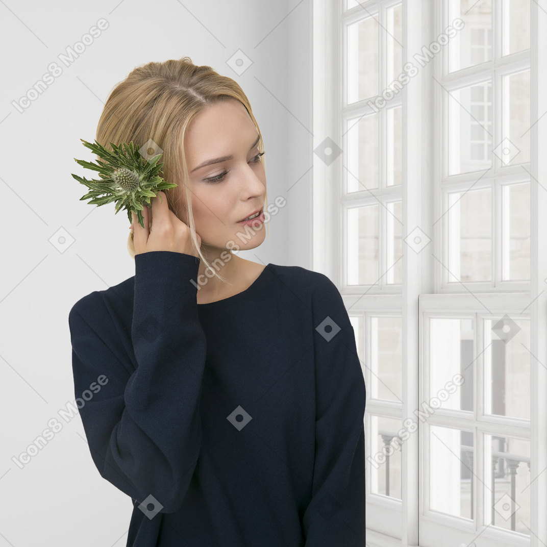 A woman holding a plant up to her ear