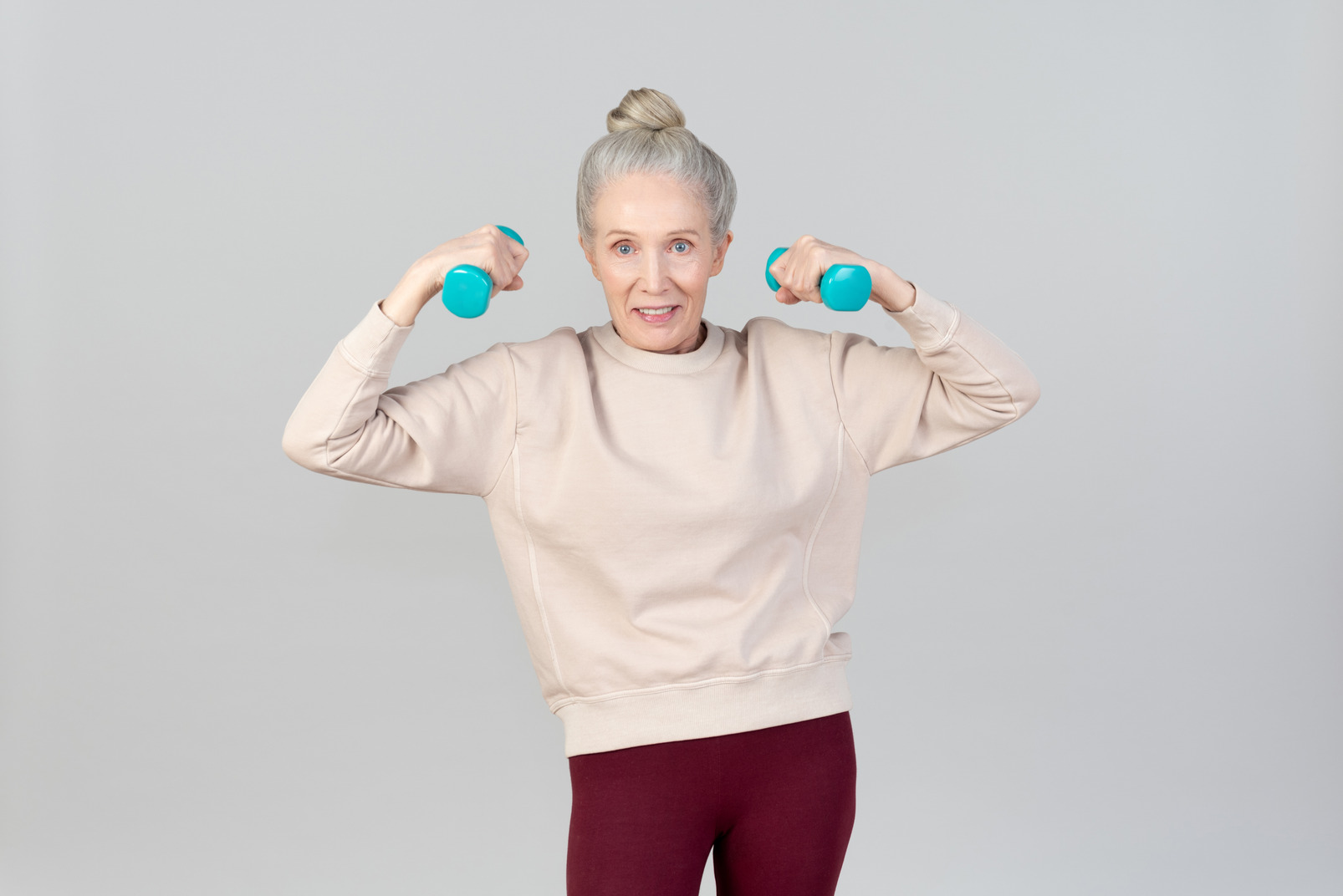 Old woman holding hand weights with her hands spread