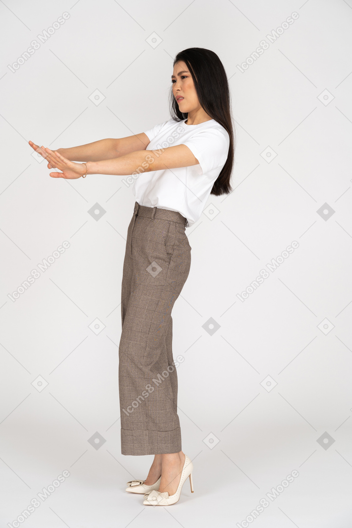 Side view of a young woman in breeches outstretching her hands