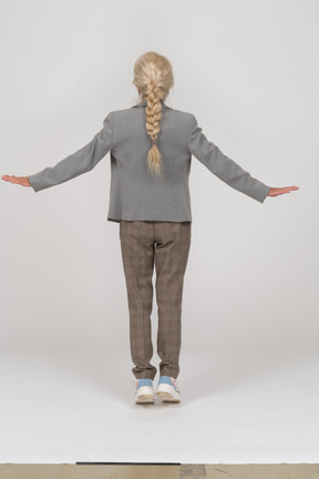 Vista posterior de una anciana en traje de pie sobre los dedos de los pies y los brazos extendidos