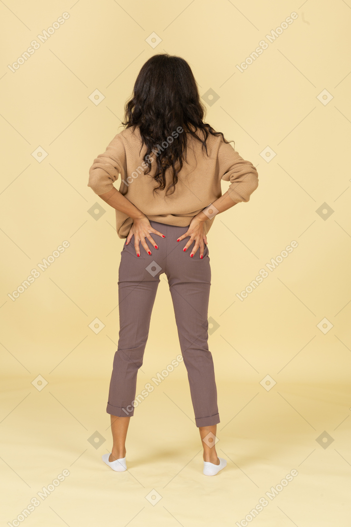 Back view of a dark-skinned young female putting hands on butt