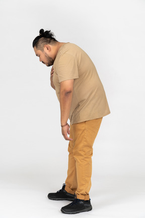 Grateful young man bowing forward with palm on his chest