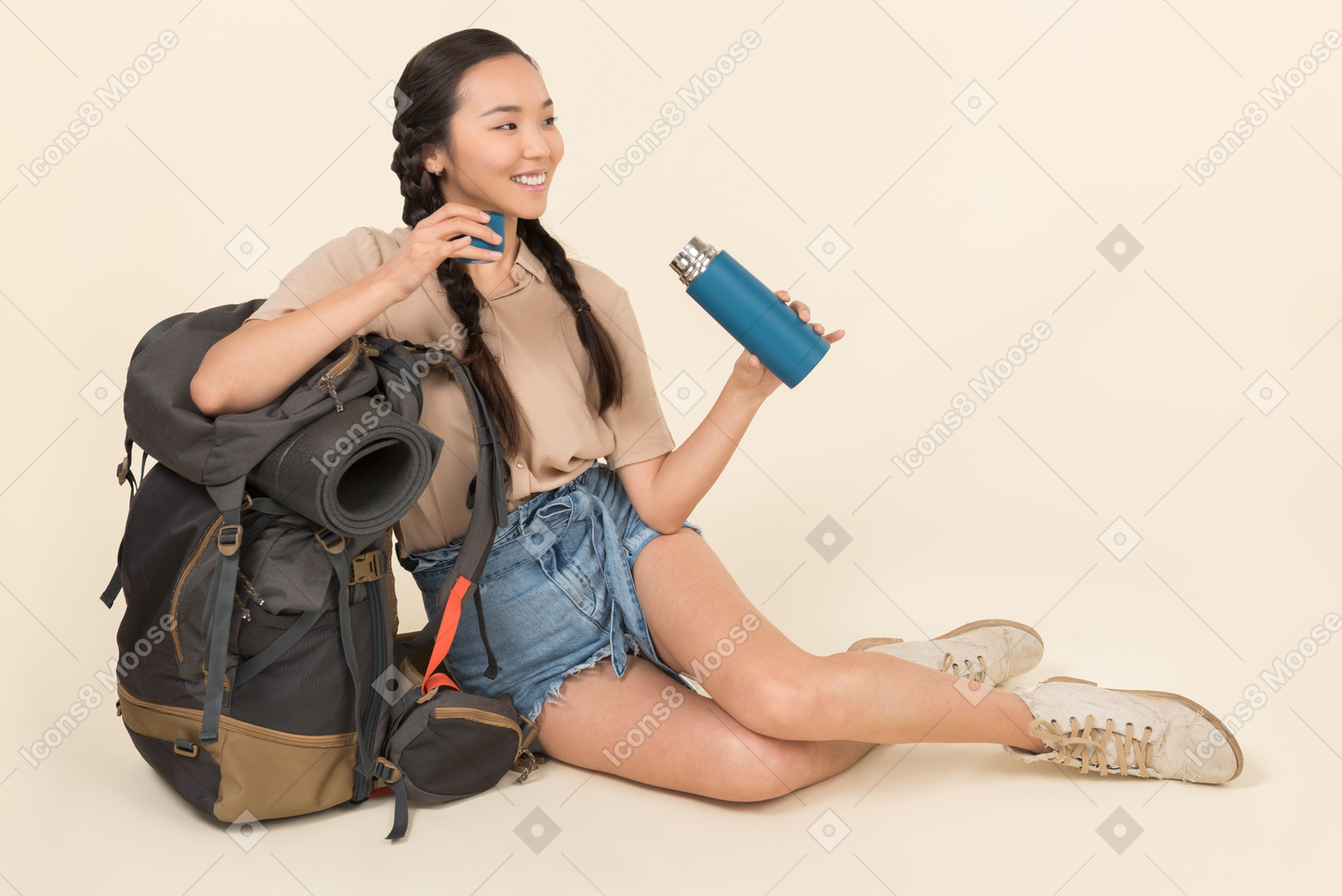 Молодая азиатская женщина сидит возле рюкзака и термос