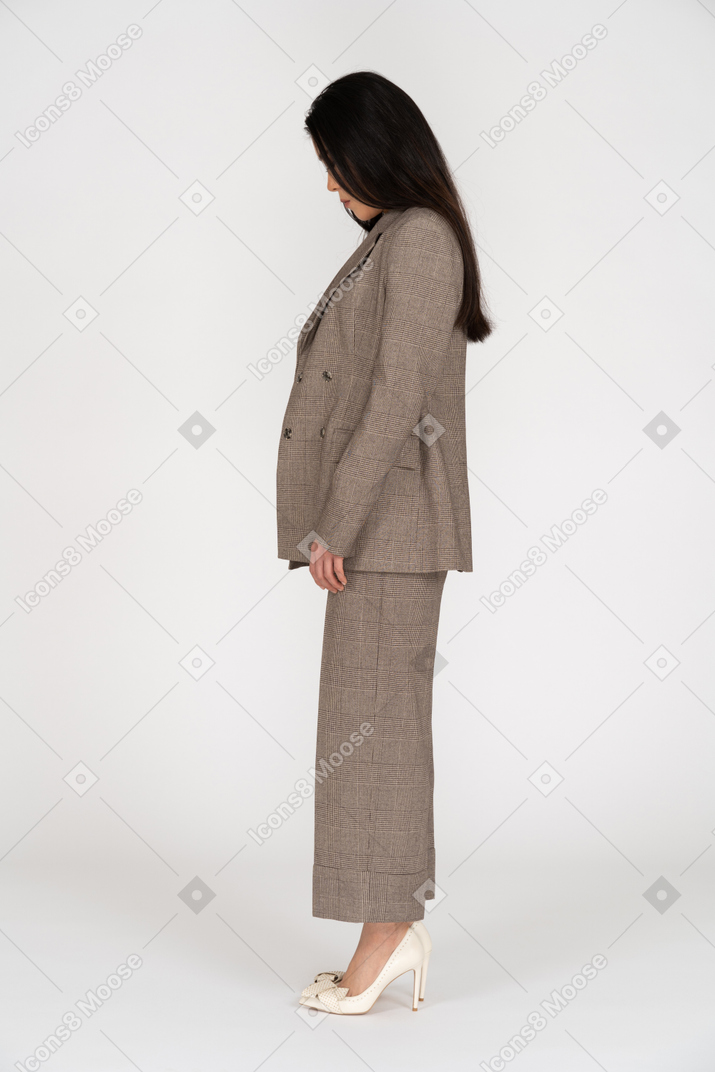Vista laterale di una giovane donna in tailleur marrone guardando verso il basso