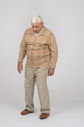 Vista frontal de um velho em roupas casuais caminhando para a frente e olhando para cima
