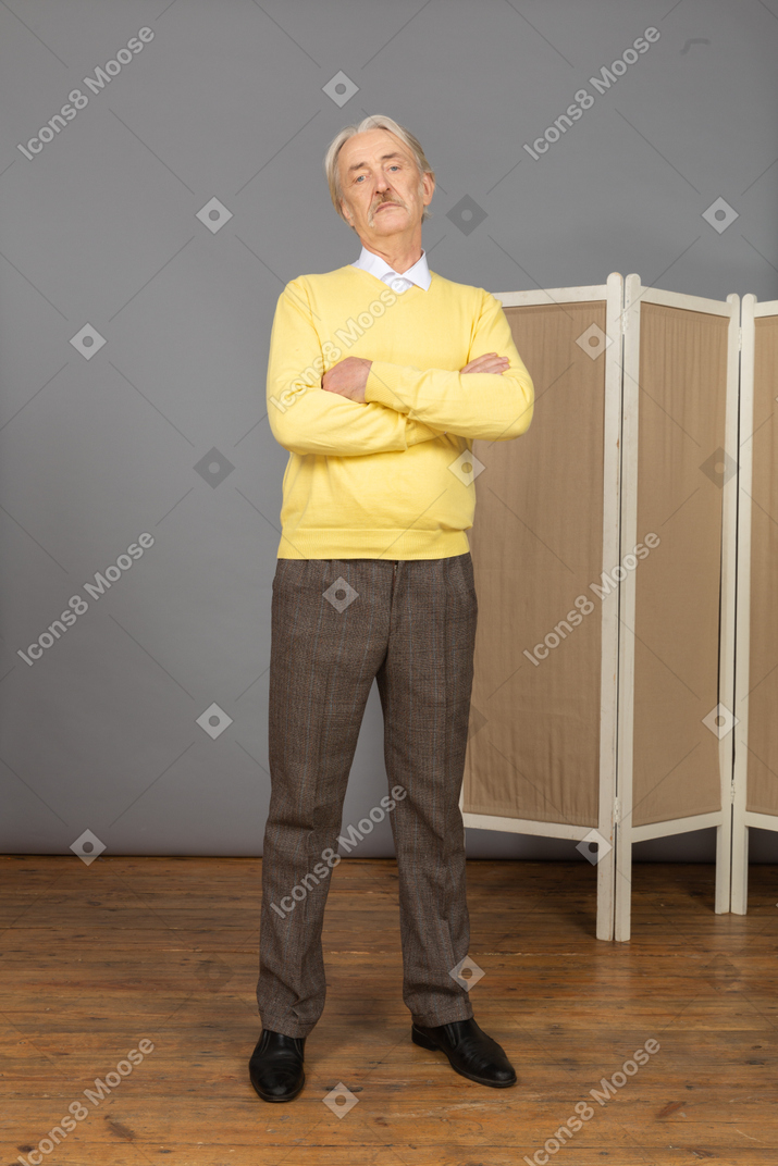 Front view of a displeased old man crossing hands