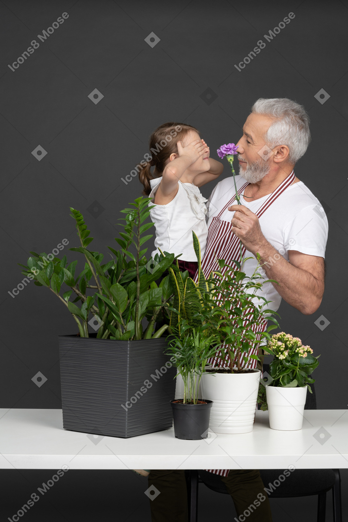 Un hombre maduro con una niña en sus manos junto a las plantas de la casa