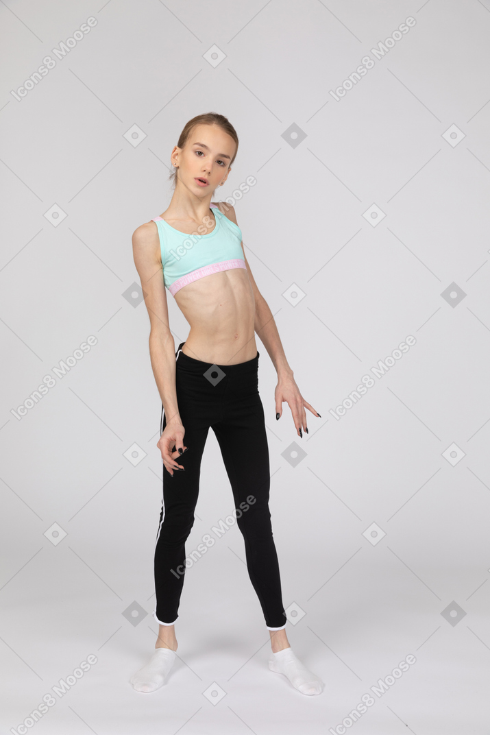 Three-quarter view of a teen girl in sportswear looking at camera while stretching back