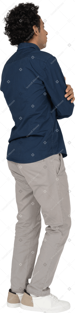 Vista laterale di un uomo in abiti casual in posa con le braccia incrociate