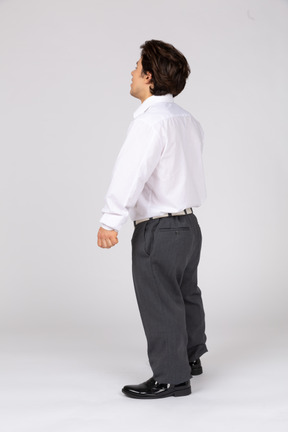 Three-quarter back view of a young office worker looking up