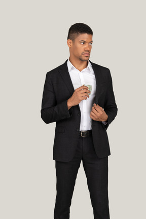 Vista frontal de um jovem de terno preto segurando o cartão do banco