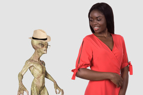 A woman in a red dress standing next to an alien