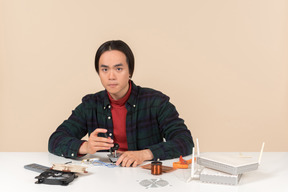 An asian geek guy in a dark checkered shirt, working with computer details