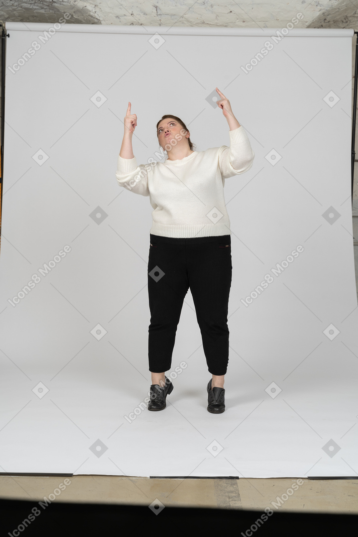 Вид спереди пухлой женщины в повседневной одежде, стоящей с поднятыми руками