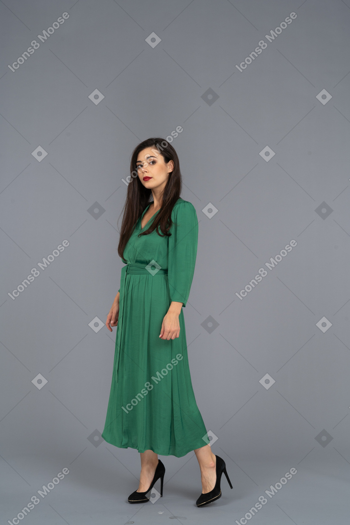 Vista di tre quarti di una giovane donna in abito verde, guardando la fotocamera