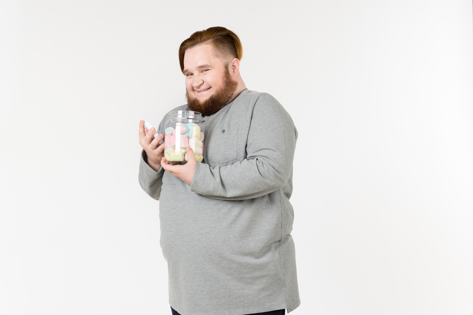 Laughing big bearded man holding jar of marshmallows