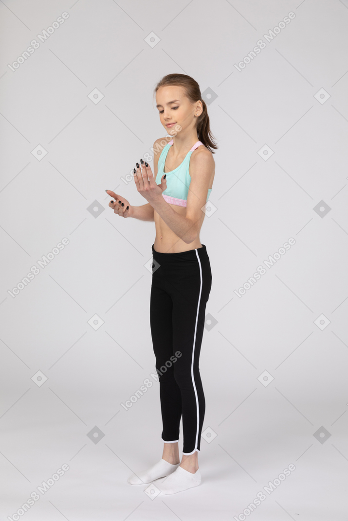 一个年轻的女孩，看着她的手的运动服的侧视图