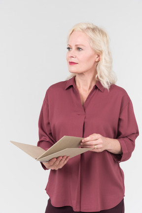 A nice-looking middle-aged blonde woman in a burgundy shirt and a craft notebook in her hand