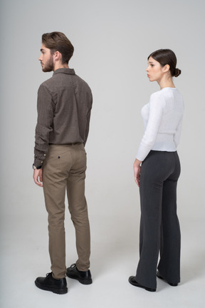 Three-quarter back view of a young couple in office clothing standing still