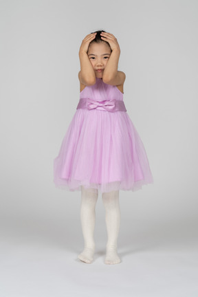 Portrait of a little girl in a lavender dress holding her head