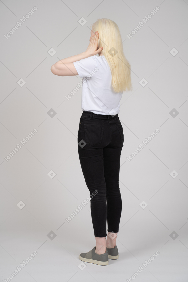 Back view of blonde woman covering her ears