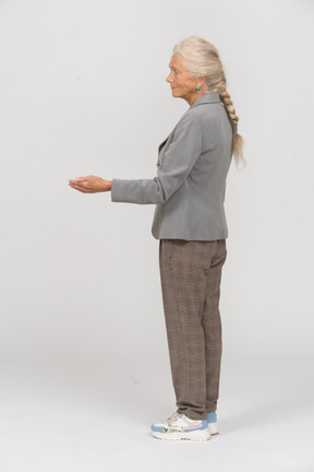 Vista lateral de una anciana en traje haciendo un gesto de bienvenida