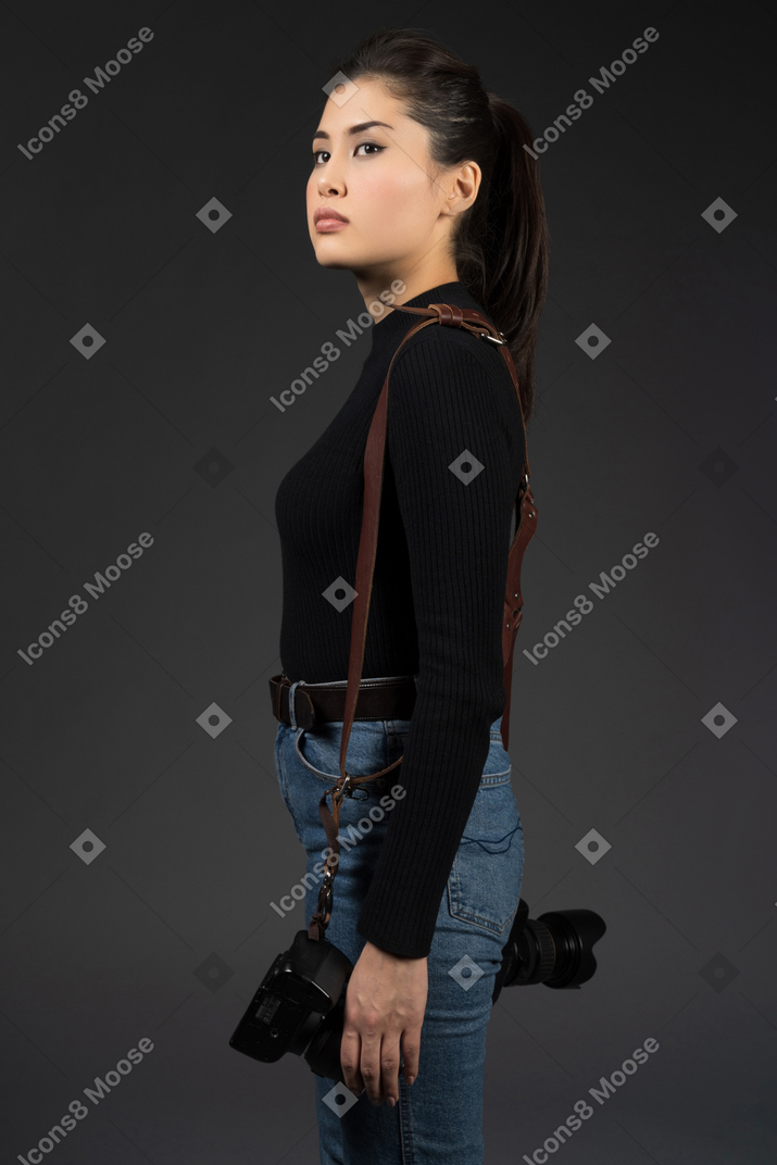 Beautiful young woman with a camera looking sideways