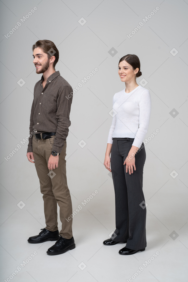 Vista de tres cuartos de una pareja joven sonriente en ropa de oficina