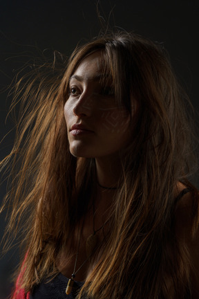 Portrait de trois quarts d'une jeune femme avec un art facial ethnique et des cheveux en désordre