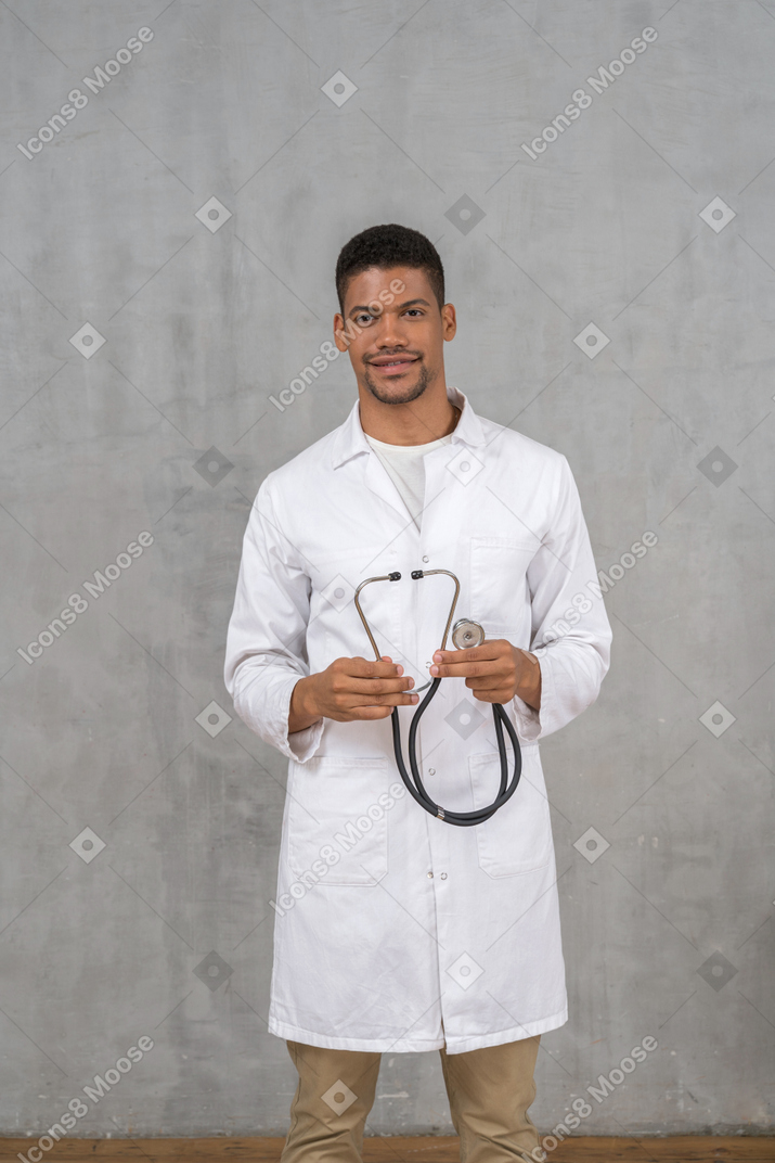Medico maschio sorridente che tiene uno stetoscopio