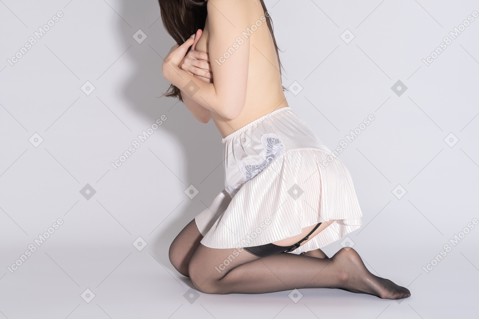 Mujer en topless irreconocible posando de rodillas