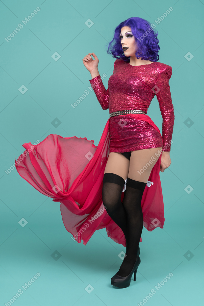Drag queen in abito rosa che cammina con una gonna lunga che scorre dietro