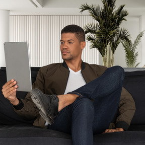 A man sitting on a couch and using tablet