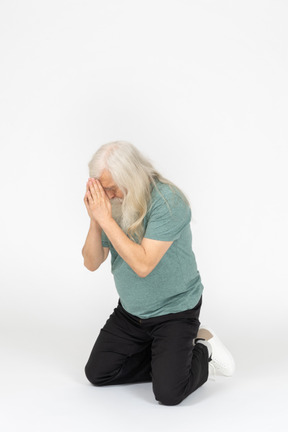 Vue de trois quarts du vieil homme assis et priant