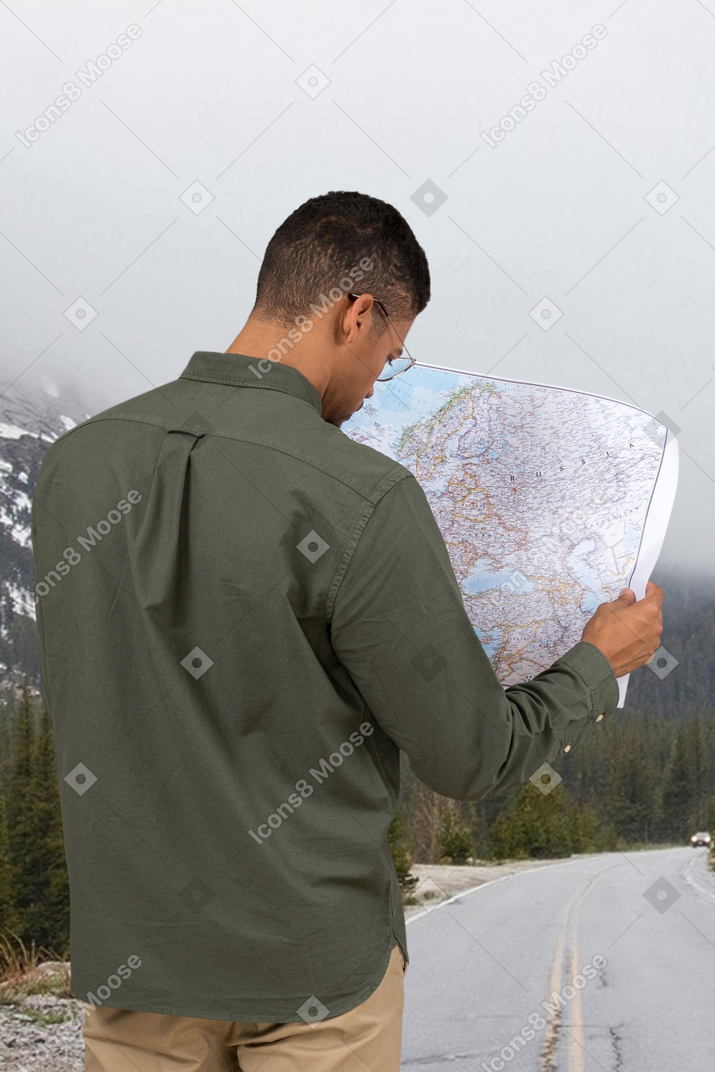 A man looking at a map on the side of a road