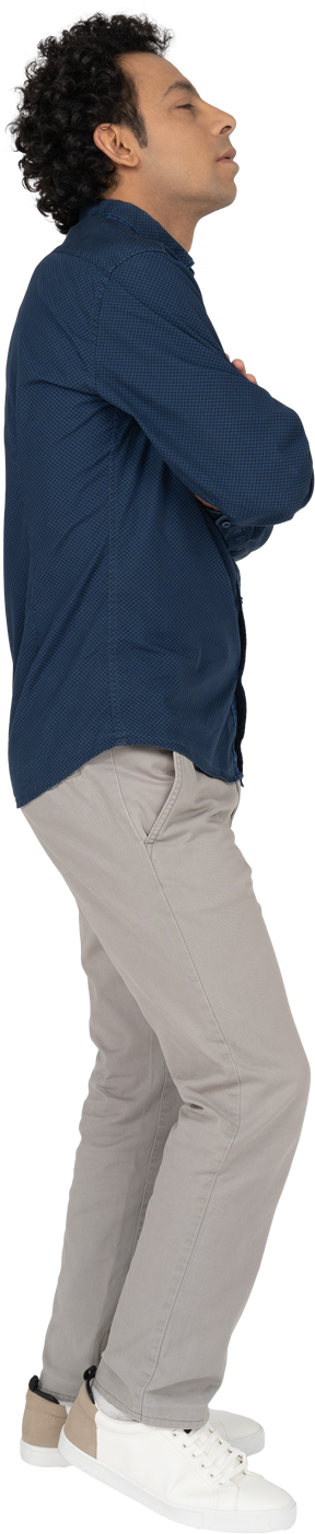 Vista laterale di un uomo in abiti casual in posa con le braccia incrociate