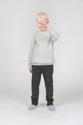 Vista frontal de um menino em roupas casuais, levantando a mão