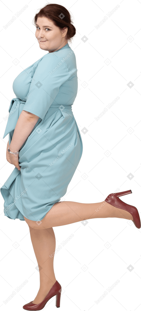一个穿着蓝色连衣裙的女人单腿站立的侧视图
