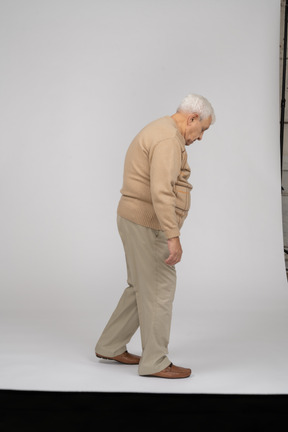 Vista lateral de un anciano con ropa informal caminando
