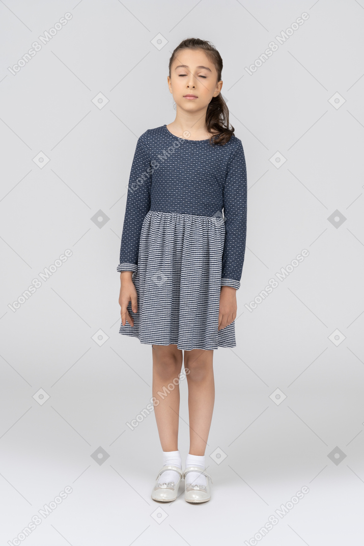 Vista frontal de una niña de pie con los ojos cerrados