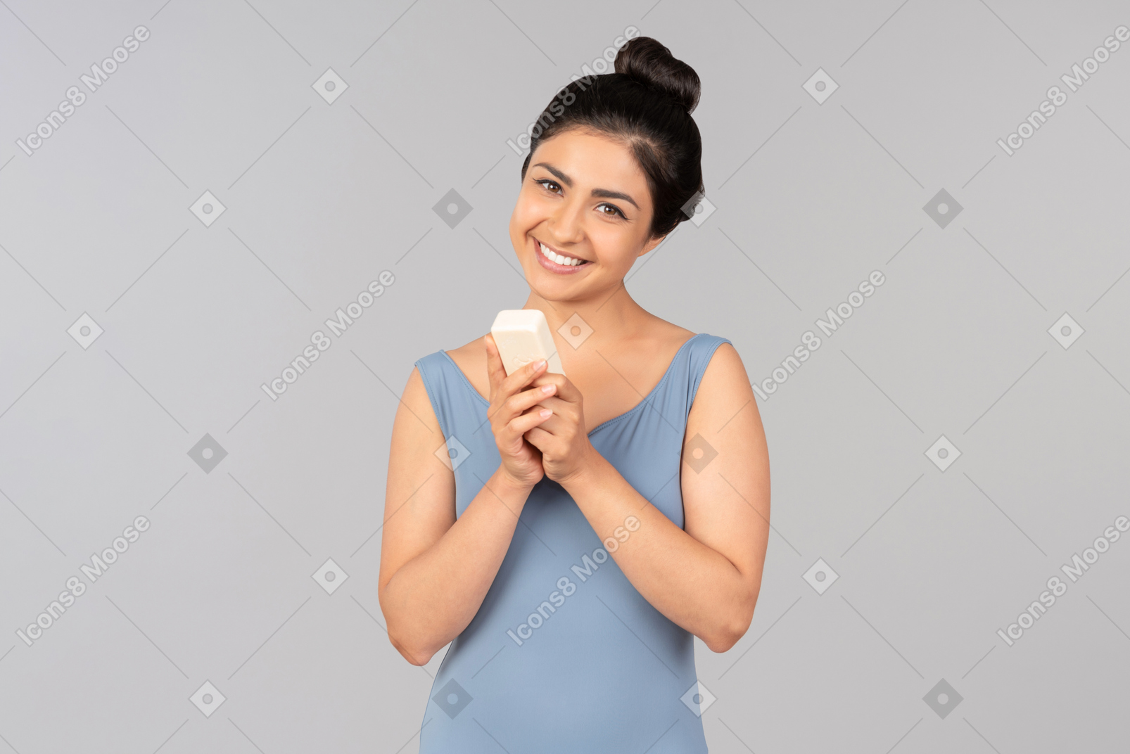 Mujer india joven sonriente que sostiene la botella cosmética