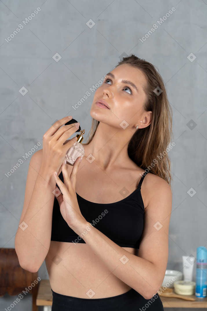 Portrait of a young woman spraying on fragrance