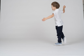Side view of a boy running around swinging his arms
