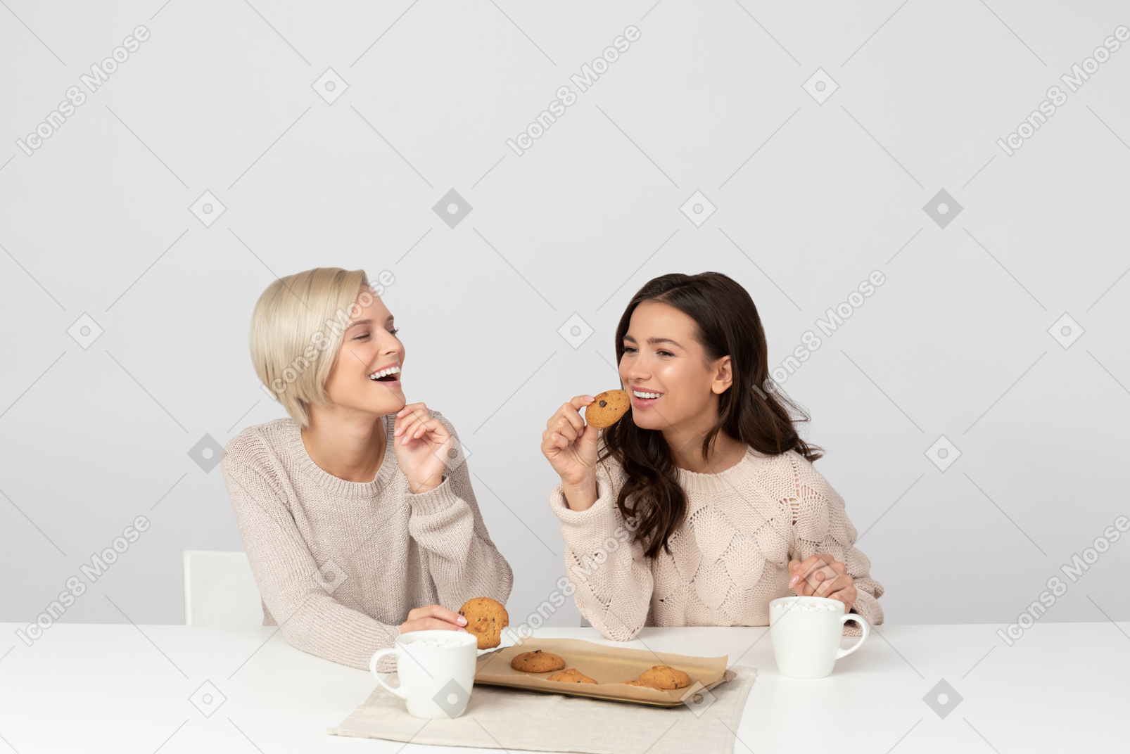 Mujeres jóvenes bebiendo café con galletas y riendo
