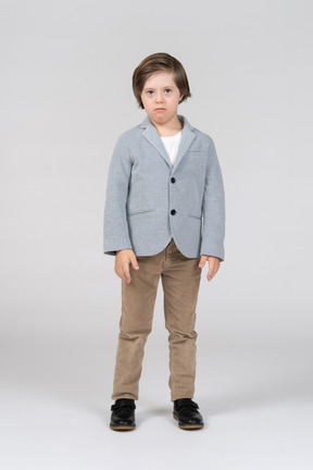 A little boy standing in a gray jacket and khaki pants