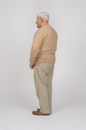 Вид сбоку на старика в повседневной одежде, стоящего с руками в карманах
