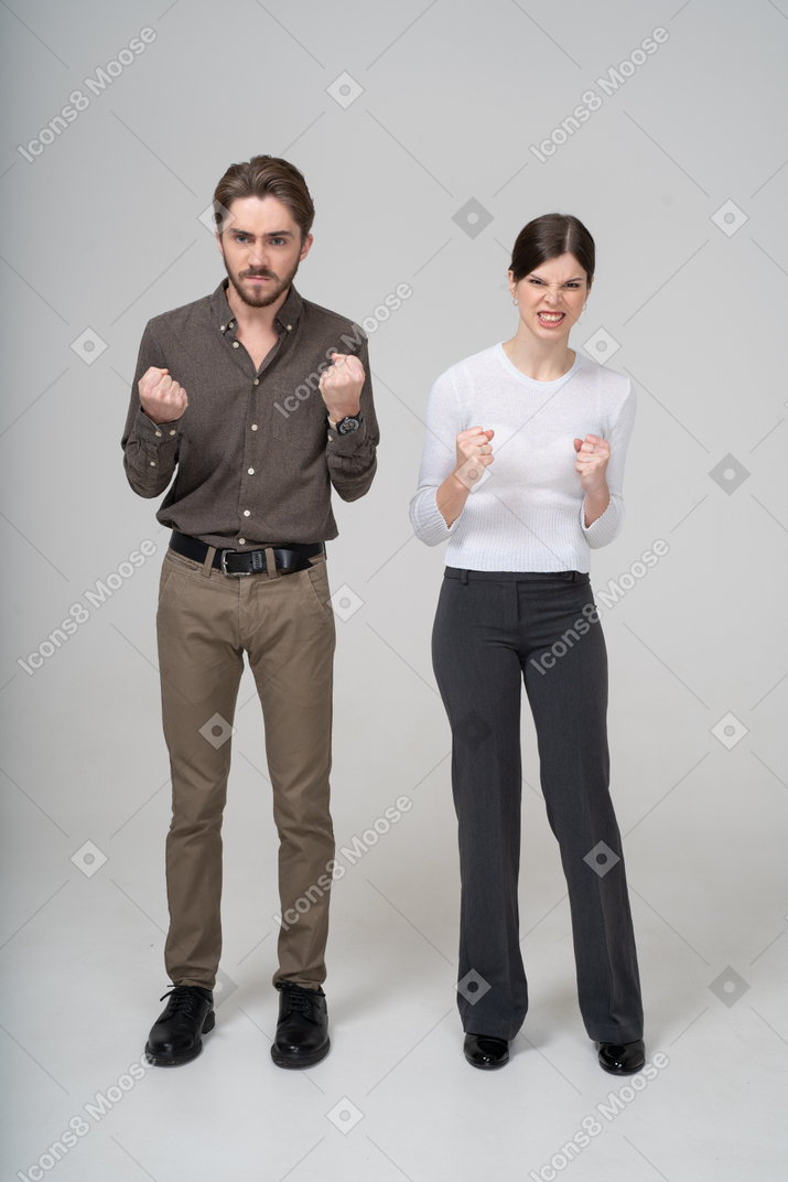 拳を食いしばっているオフィス服の猛烈なカップルの正面図