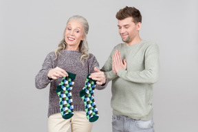 Elegant old woman giving socks as a present to a young guy